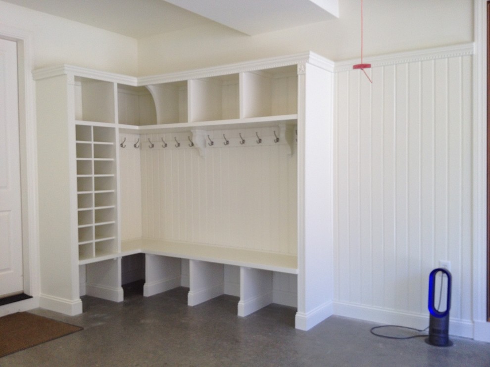 This is an example of a mid-sized traditional mudroom in Charlotte with white walls, concrete floors, a single front door and a medium wood front door.