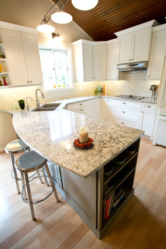Mid-sized transitional u-shaped light wood floor kitchen photo in Toronto with an undermount sink, shaker cabinets, white cabinets, granite countertops, white backsplash, subway tile backsplash, white appliances and a peninsula