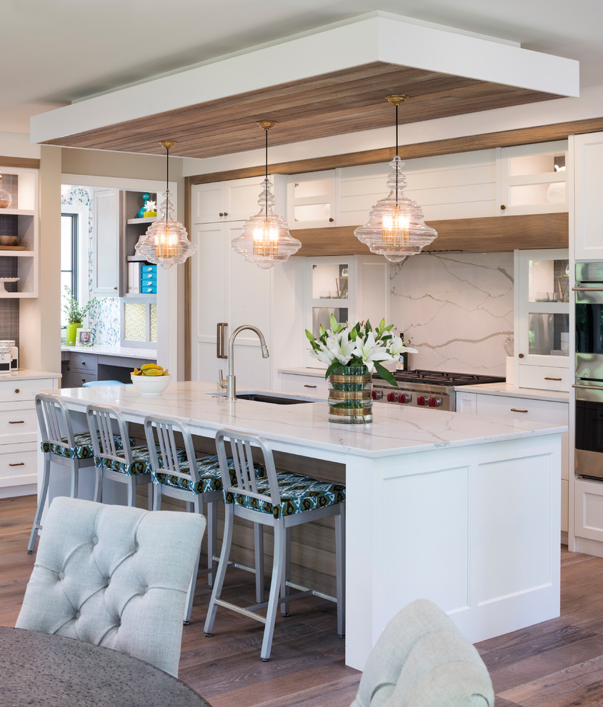 Large transitional single-wall dark wood floor and brown floor eat-in kitchen photo in Minneapolis with an undermount sink, shaker cabinets, white cabinets, marble countertops, white backsplash, stone slab backsplash, stainless steel appliances and an island
