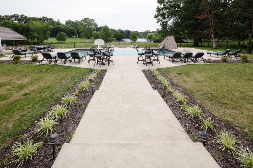 Photo of a large country backyard rectangular infinity pool in Kansas City with a water slide and stamped concrete.