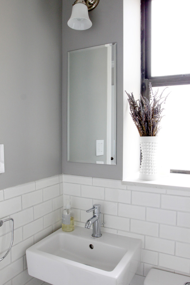 Transitional bathroom in New York with a console sink, an alcove shower, a one-piece toilet, white tile, ceramic tile, grey walls and mosaic tile floors.