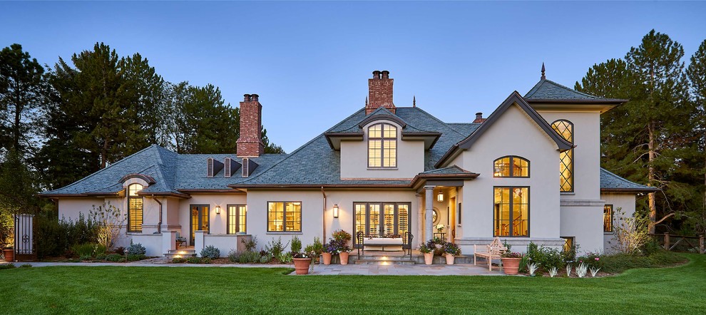 Large traditional two-storey stucco grey house exterior in Denver with a hip roof and a tile roof.