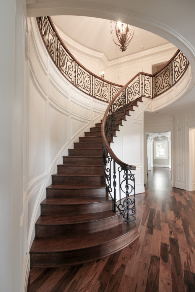 Photo of a large eclectic wood curved staircase in DC Metro with wood risers and mixed railing.