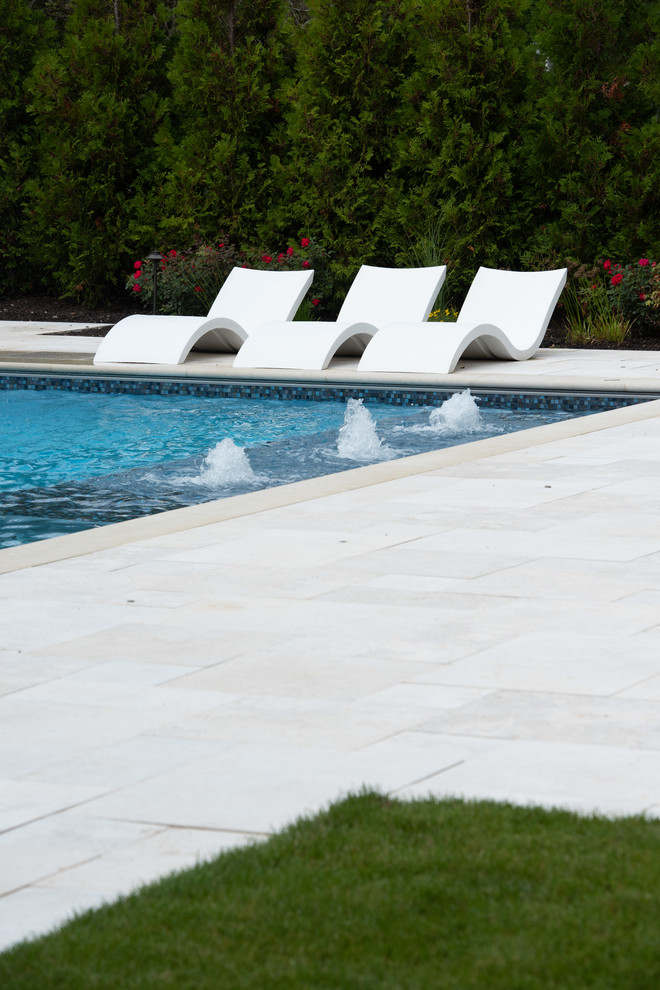 Large traditional backyard rectangular pool in Chicago with a water feature and natural stone pavers.