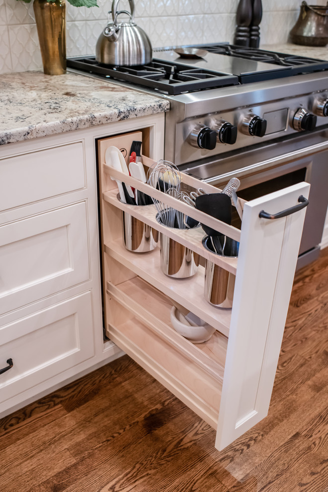 Inspiration for a mid-sized traditional l-shaped separate kitchen in Portland Maine with an undermount sink, recessed-panel cabinets, white cabinets, granite benchtops, white splashback, panelled appliances, medium hardwood floors, with island, brown floor and beige benchtop.