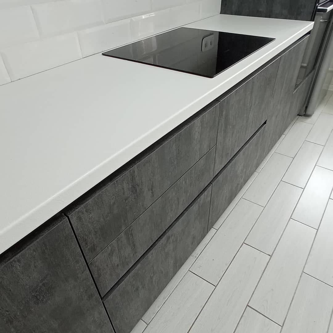 Широкая угловая черно-белая кухня с фасадами под камень