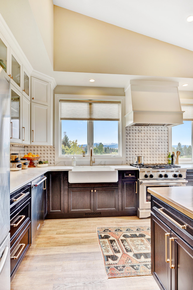 Mid-sized transitional l-shaped vinyl floor and brown floor eat-in kitchen photo with a farmhouse sink, recessed-panel cabinets, dark wood cabinets, quartzite countertops, white backsplash, marble backsplash, stainless steel appliances and an island
