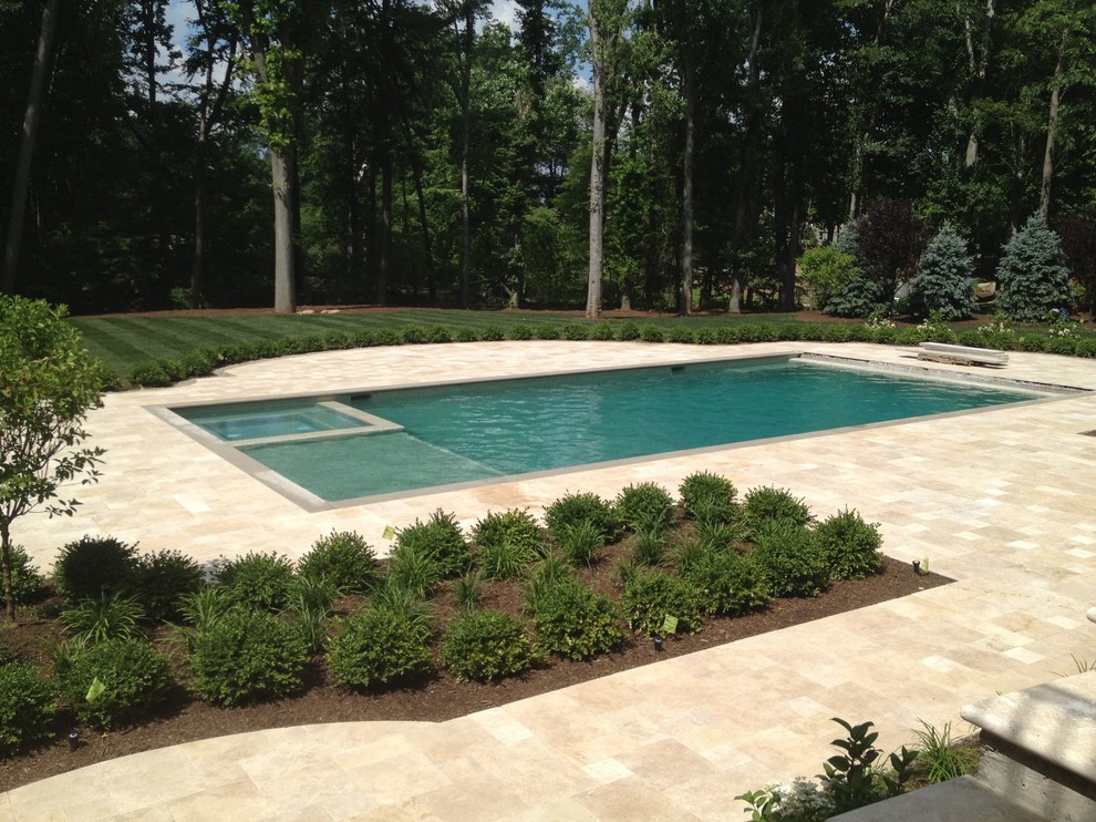 This is an example of an expansive traditional courtyard rectangular pool in New York with natural stone pavers.