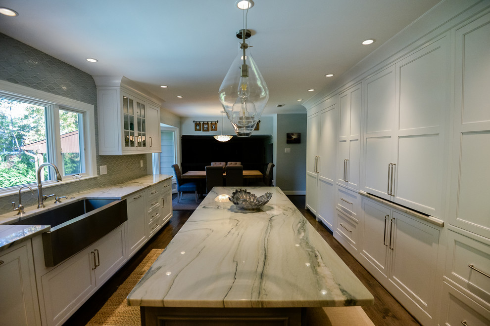 Large transitional u-shaped medium tone wood floor and brown floor eat-in kitchen photo in DC Metro with a farmhouse sink, recessed-panel cabinets, white cabinets, marble countertops, stainless steel appliances, an island, gray backsplash and porcelain backsplash