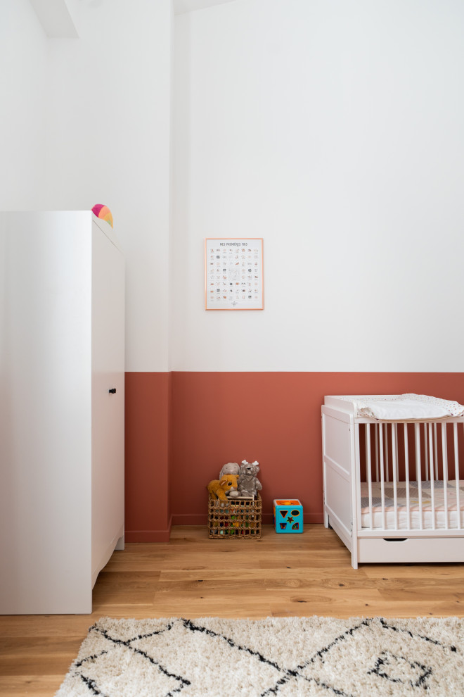 Aménagement d'une grande chambre de bébé neutre moderne avec un mur blanc et parquet clair.
