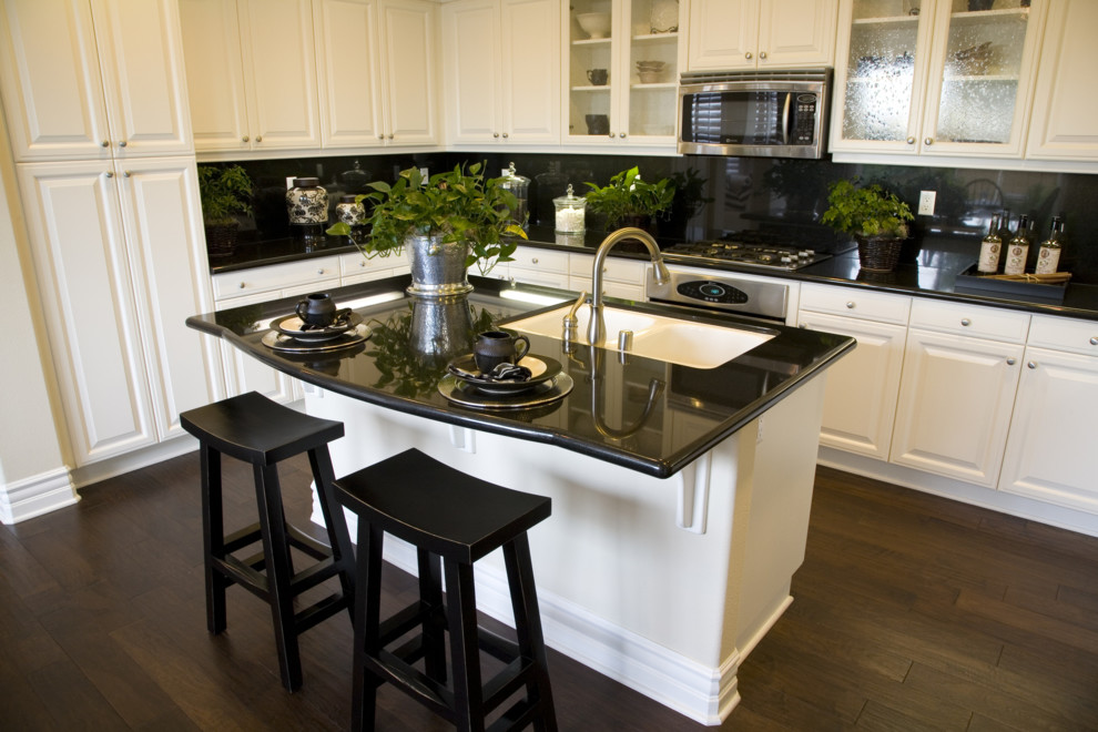 Eat-in kitchen - traditional u-shaped eat-in kitchen idea in Philadelphia with an undermount sink, raised-panel cabinets, white cabinets, granite countertops, black backsplash, stone slab backsplash and stainless steel appliances