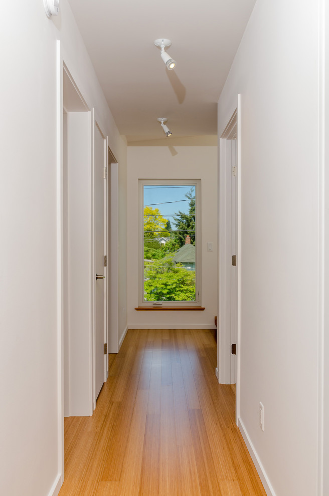 Inspiration for a mid-sized modern hallway in Seattle with white walls and bamboo floors.