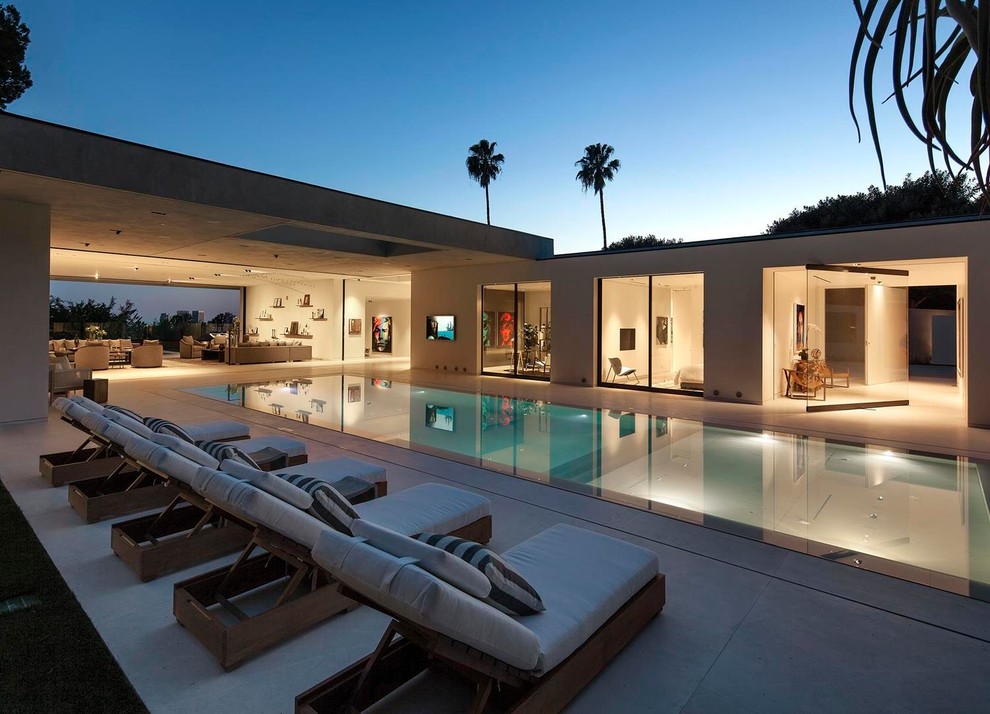 Photo of an expansive contemporary backyard rectangular infinity pool in Los Angeles with a hot tub and concrete slab.