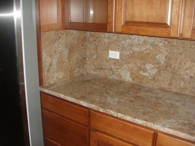 Inspiration for a mid-sized kitchen remodel in Phoenix with raised-panel cabinets, medium tone wood cabinets, granite countertops, beige backsplash, stone slab backsplash and an island