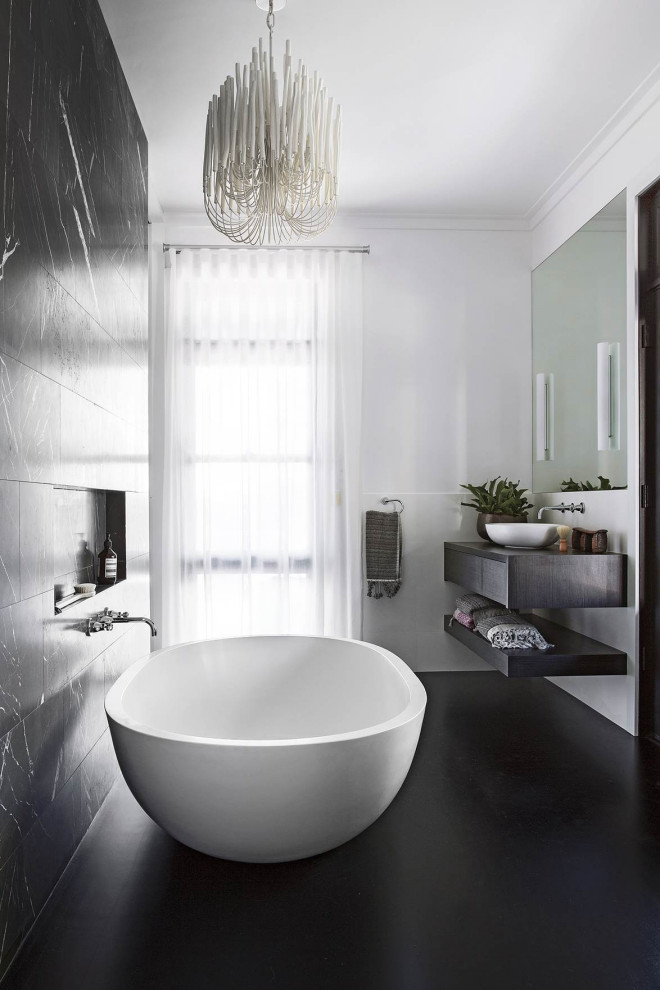 Inredning av ett modernt badrum, med luckor med infälld panel, ett fristående badkar, svart kakel, vita väggar, ett fristående handfat och svart golv