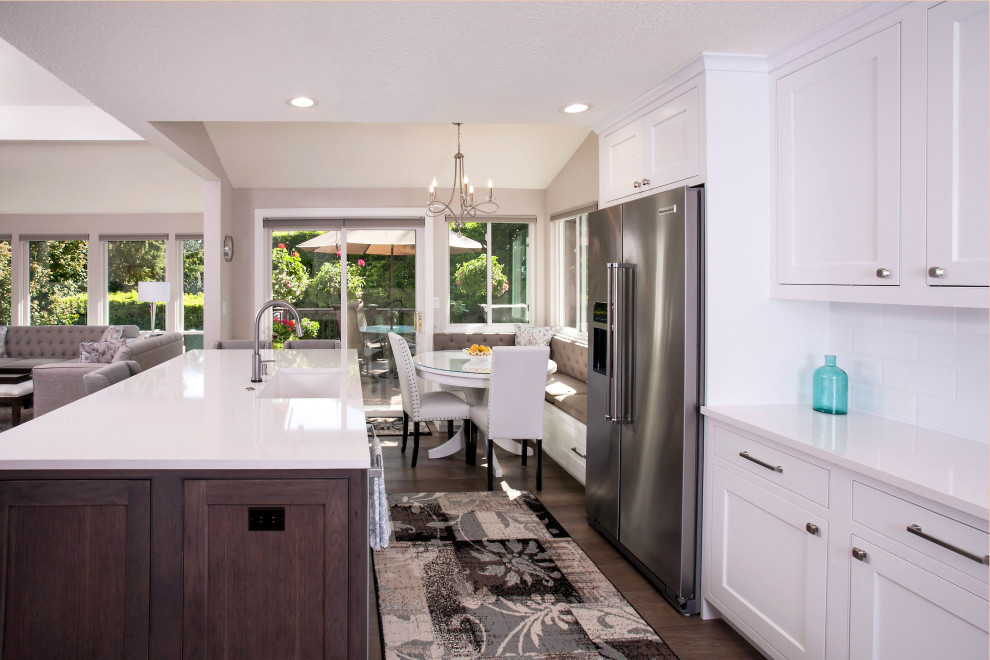 Inspiration for a large transitional l-shaped medium tone wood floor and brown floor open concept kitchen remodel in Seattle with an undermount sink, beaded inset cabinets, white cabinets, quartz countertops, white backsplash, ceramic backsplash, stainless steel appliances, an island and white countertops