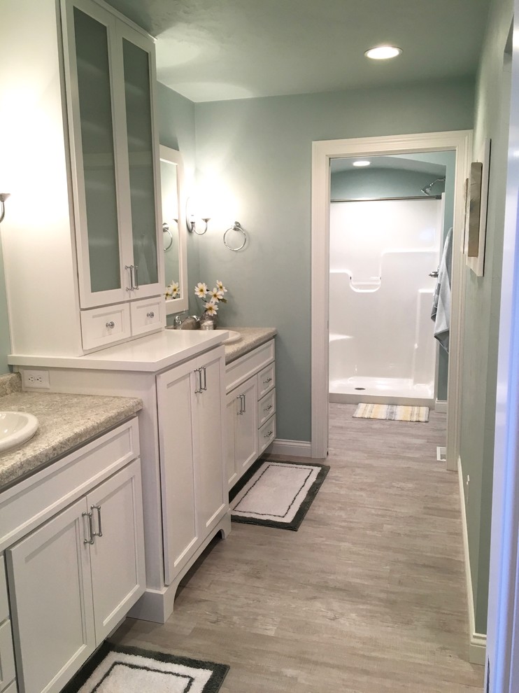 This is an example of a large arts and crafts master bathroom in Other with recessed-panel cabinets, white cabinets, a curbless shower, blue walls, vinyl floors, a drop-in sink and laminate benchtops.