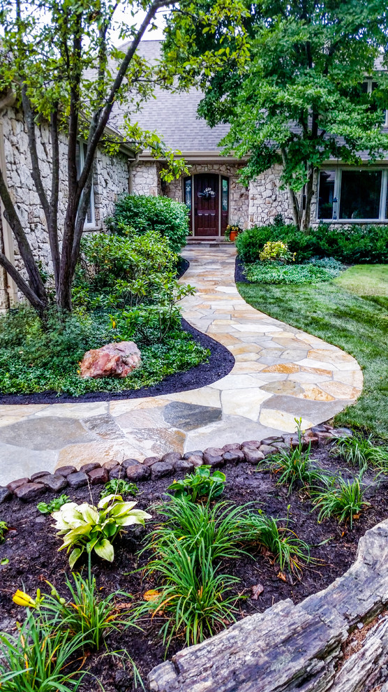 Photo of a large traditional front yard garden with a garden path and natural stone pavers.