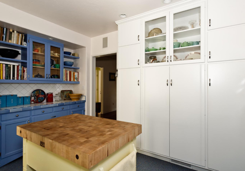 Photo of a mid-sized eclectic kitchen pantry in San Francisco with shaker cabinets, blue cabinets, tile benchtops, white splashback, ceramic splashback and terrazzo floors.