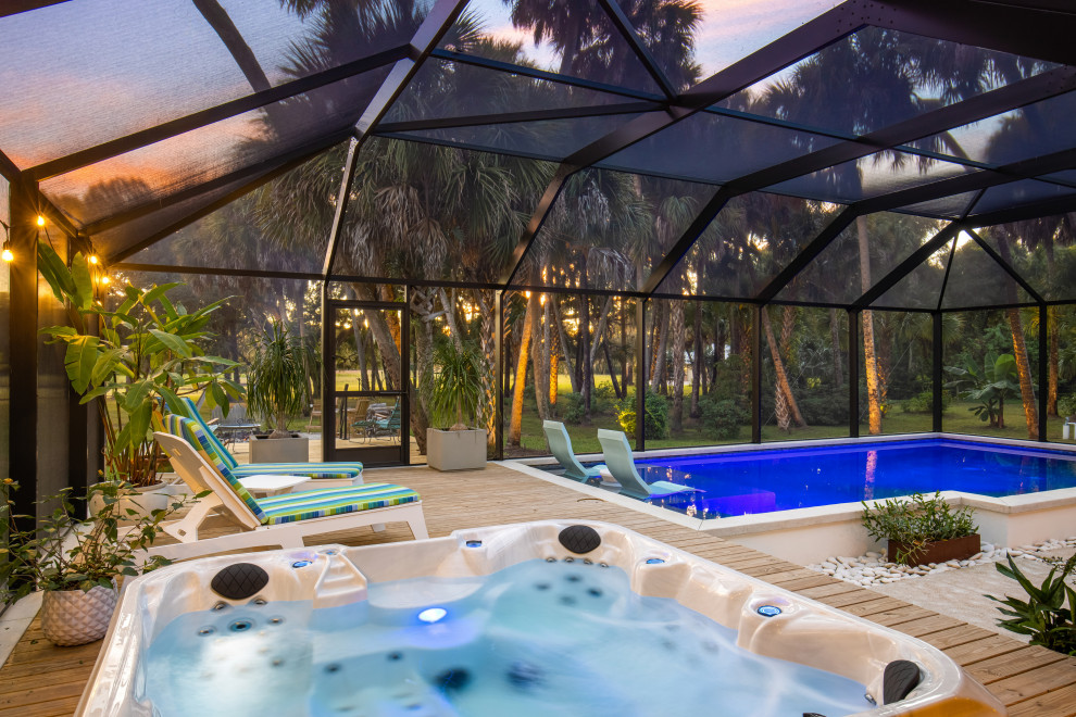 Ejemplo de piscina campestre extra grande rectangular en patio trasero con losas de hormigón