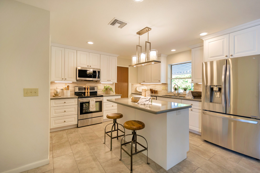 Inspiration for a large transitional l-shaped porcelain tile open concept kitchen remodel in Phoenix with an undermount sink, raised-panel cabinets, white cabinets, quartz countertops, beige backsplash, porcelain backsplash, stainless steel appliances and an island