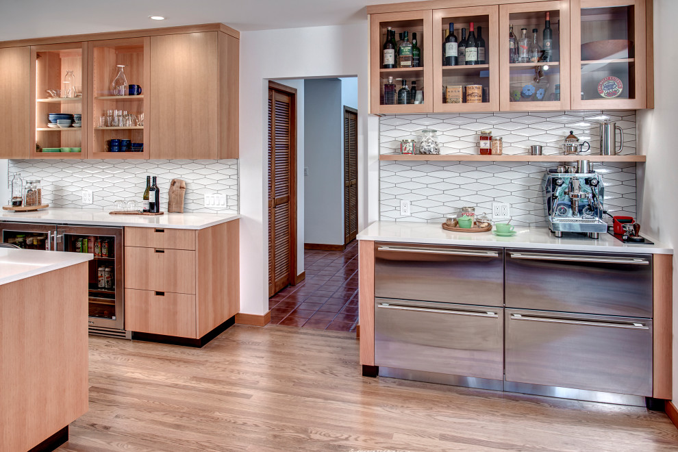 Inspiration for a large modern kitchen in Seattle with an undermount sink, flat-panel cabinets, light wood cabinets, quartz benchtops, white splashback, porcelain splashback, stainless steel appliances, light hardwood floors, with island and white benchtop.
