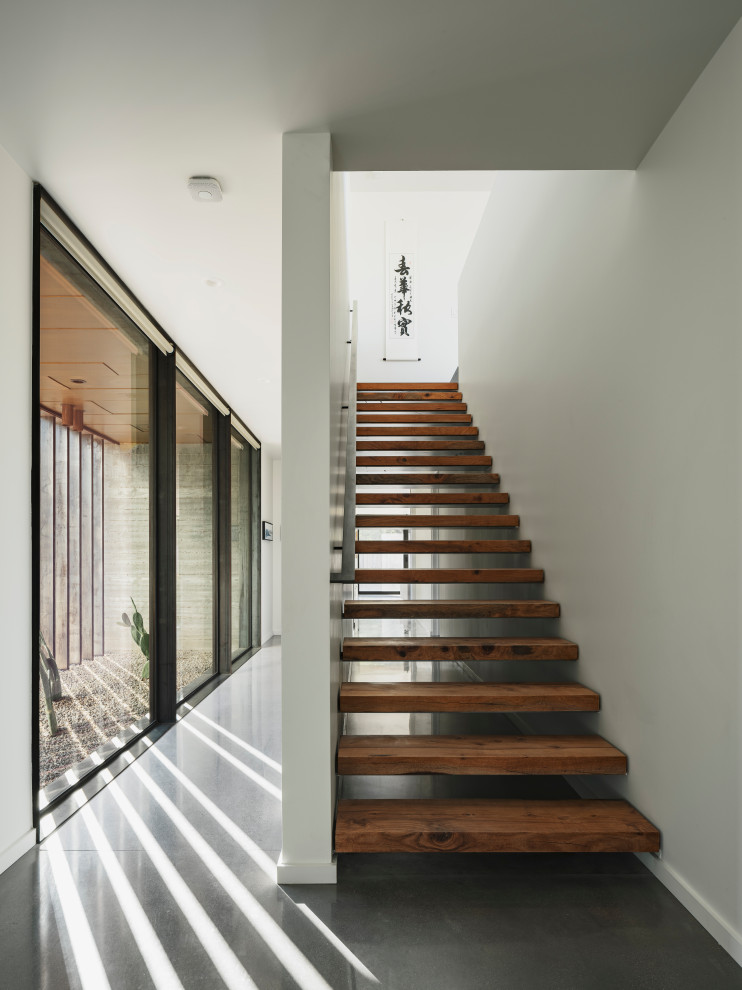 На фото: лестница на больцах в стиле модернизм с деревянными ступенями и металлическими перилами без подступенок с