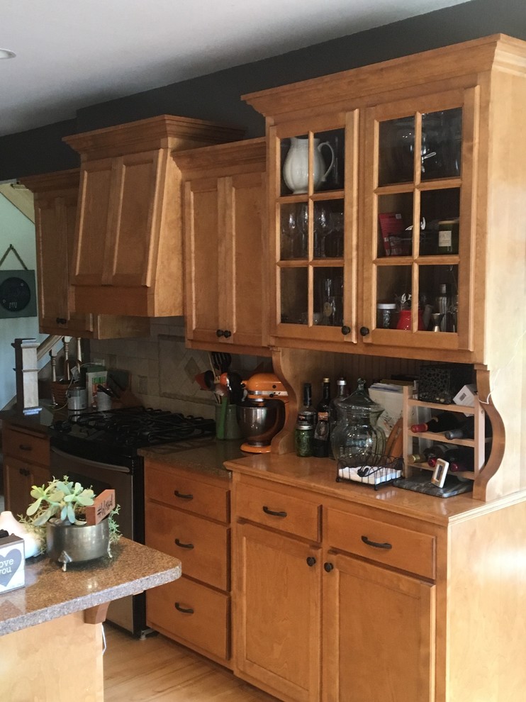 Inspiration for a mid-sized u-shaped light wood floor eat-in kitchen remodel with recessed-panel cabinets, medium tone wood cabinets, granite countertops, beige backsplash, stainless steel appliances and an island