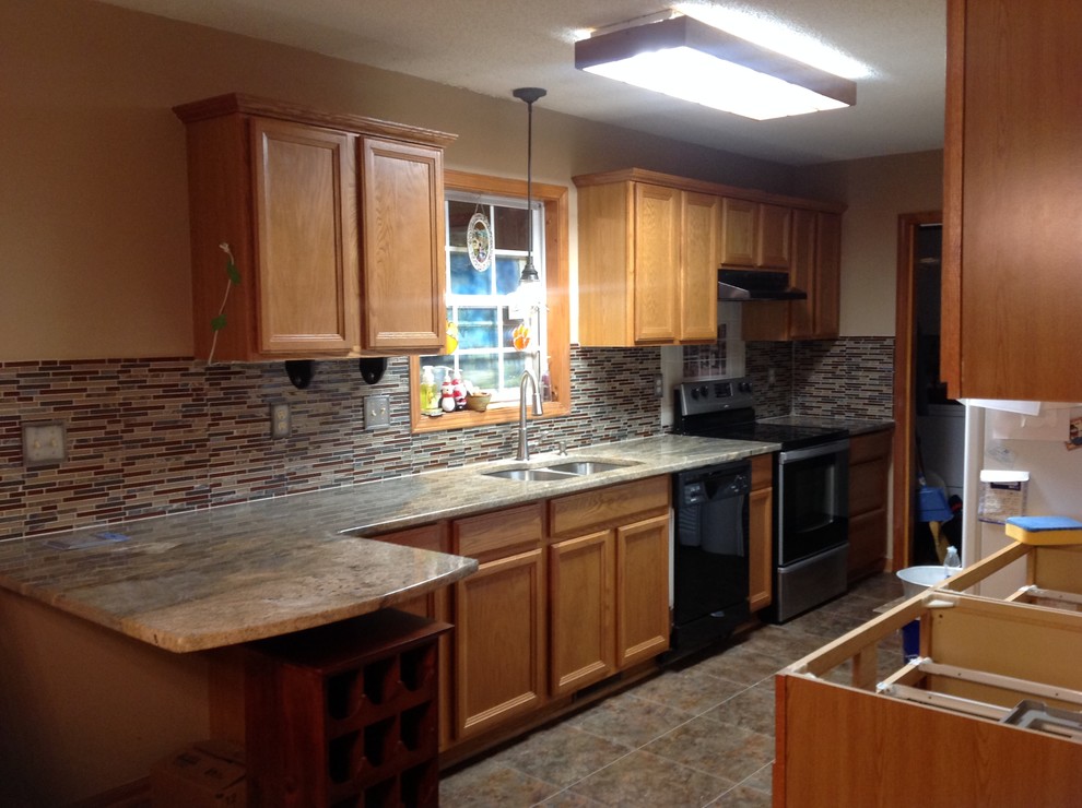 Inspiration for a l-shaped eat-in kitchen remodel with an undermount sink, flat-panel cabinets, brown backsplash, glass tile backsplash, stainless steel appliances and a peninsula