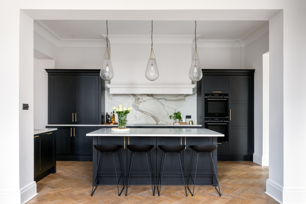 Design ideas for a large classic open plan kitchen in Other with a belfast sink, shaker cabinets, black cabinets, quartz worktops, white splashback, stone slab splashback, integrated appliances, an island and white worktops.
