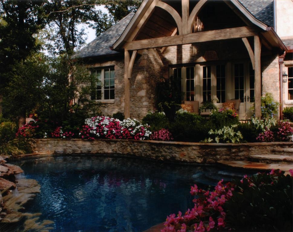 Inspiration for a large traditional backyard custom-shaped infinity pool in Other with a hot tub and natural stone pavers.