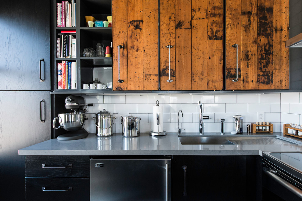Mid-sized industrial u-shaped separate kitchen in San Francisco with an undermount sink, flat-panel cabinets, black cabinets, quartz benchtops, white splashback, subway tile splashback, stainless steel appliances and a peninsula.