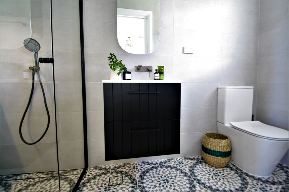 Mid-sized eclectic bathroom in Sydney with black cabinets, a one-piece toilet, gray tile, porcelain tile, terrazzo floors, solid surface benchtops, white benchtops, a single vanity and a floating vanity.