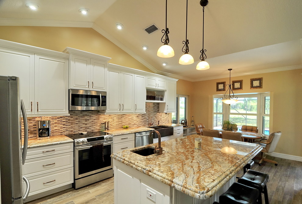 Eat-in kitchen - transitional medium tone wood floor and multicolored floor eat-in kitchen idea in Miami with a farmhouse sink, recessed-panel cabinets, white cabinets, granite countertops, multicolored backsplash, ceramic backsplash, stainless steel appliances and an island