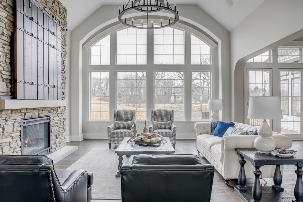 Inspiration for a large traditional open concept family room in Minneapolis with grey walls, dark hardwood floors, a standard fireplace, a stone fireplace surround, a concealed tv and brown floor.