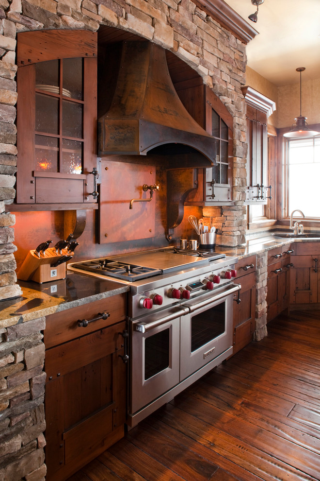 Country l-shaped kitchen in Denver with an undermount sink, dark wood cabinets, granite benchtops, brown splashback, metal splashback, stainless steel appliances and shaker cabinets.