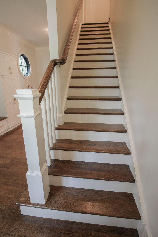 This is an example of a large transitional wood u-shaped staircase in DC Metro with wood risers, wood railing and decorative wall panelling.