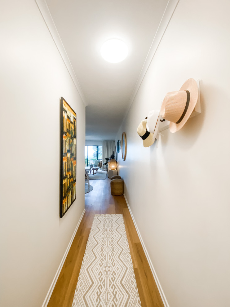 Modelo de recibidores y pasillos costeros pequeños con paredes blancas, suelo de madera en tonos medios y suelo marrón