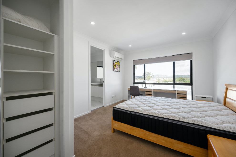 Cette image montre une très grande chambre minimaliste avec un mur blanc, aucune cheminée et un sol marron.