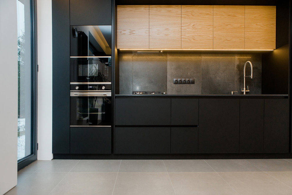 Inspiration for a medium sized contemporary single-wall kitchen in Other with composite countertops, grey splashback, black appliances and ceramic flooring.