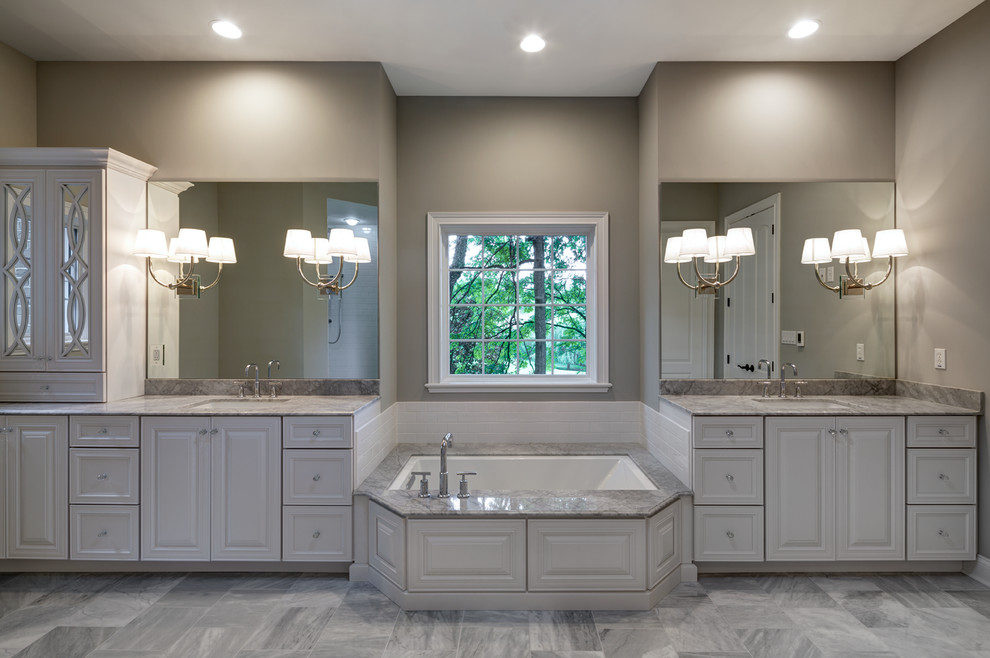 Inspiration for a traditional master bathroom in St Louis with an undermount sink, raised-panel cabinets, white cabinets, marble benchtops, an undermount tub, an alcove shower, a two-piece toilet, white tile, ceramic tile, grey walls and marble floors.