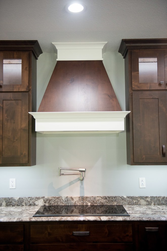 Example of a transitional l-shaped open concept kitchen design with an undermount sink, shaker cabinets, dark wood cabinets, granite countertops, stainless steel appliances, an island and multicolored countertops