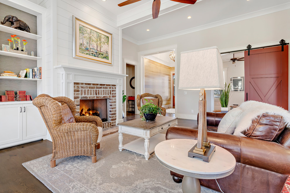 Large country open concept living room in Charleston with beige walls, brick floors, a standard fireplace, a brick fireplace surround and brown floor.
