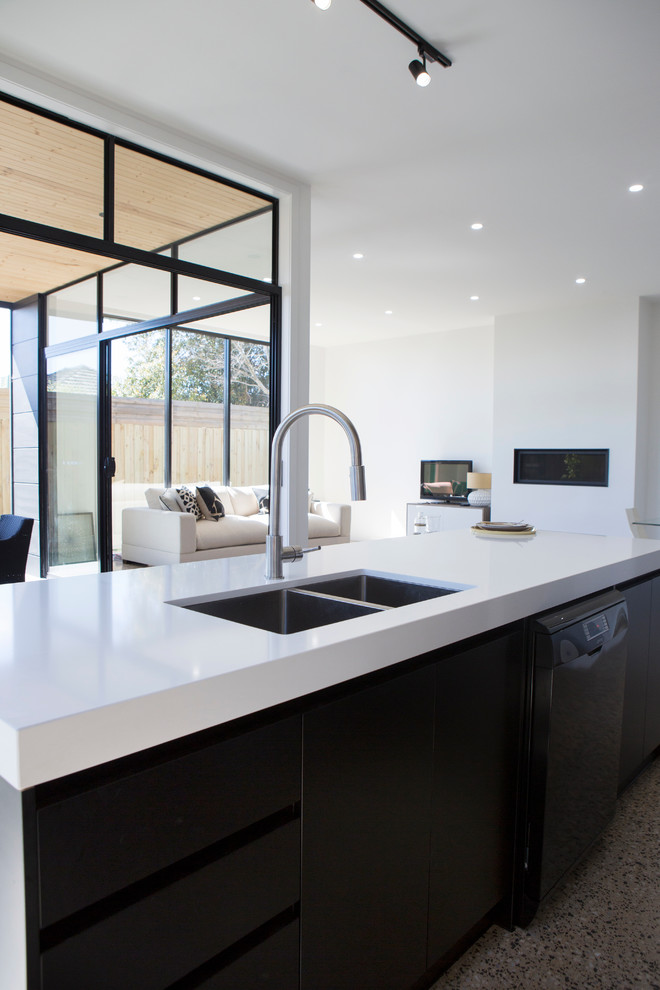 Design ideas for a mid-sized contemporary single-wall open plan kitchen in Melbourne with black cabinets, quartz benchtops, grey splashback, glass sheet splashback, black appliances, concrete floors, with island, a double-bowl sink and flat-panel cabinets.