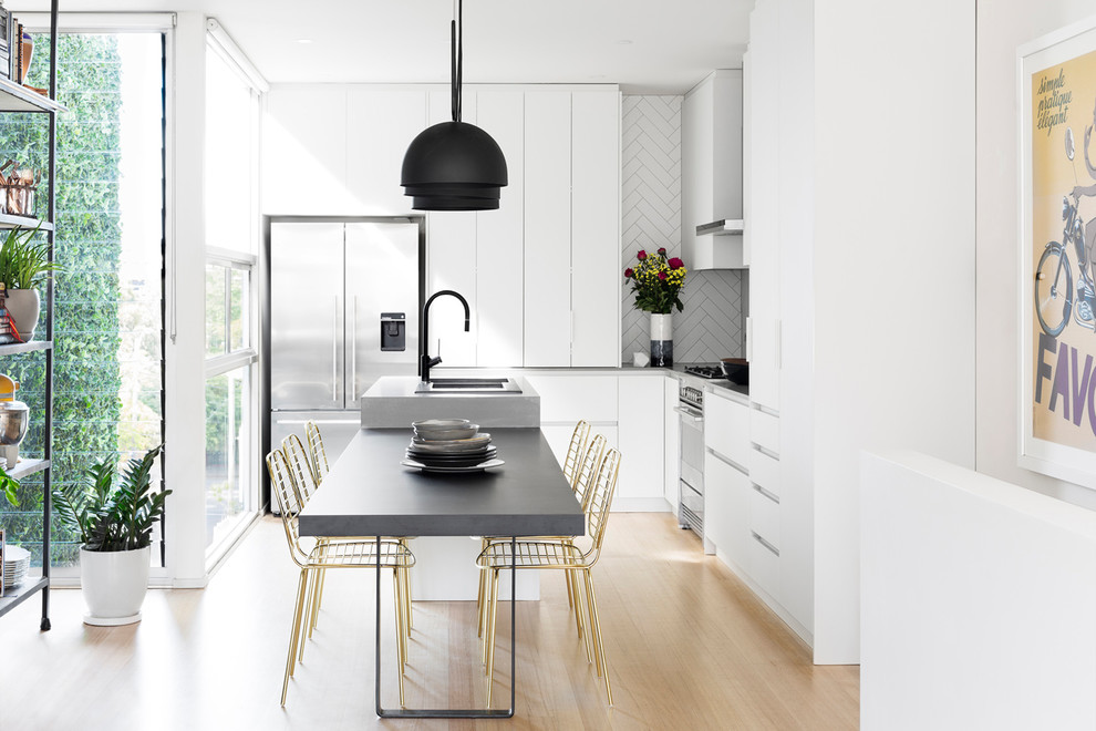 Inspiration for a contemporary l-shaped eat-in kitchen in Melbourne with a double-bowl sink, flat-panel cabinets, white splashback, stainless steel appliances, light hardwood floors, with island and beige floor.