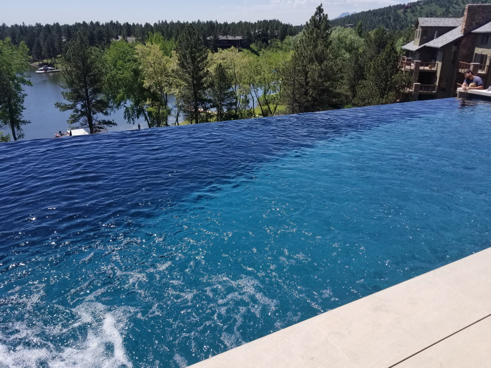 Example of a mid-sized backyard rectangular infinity hot tub design in Denver
