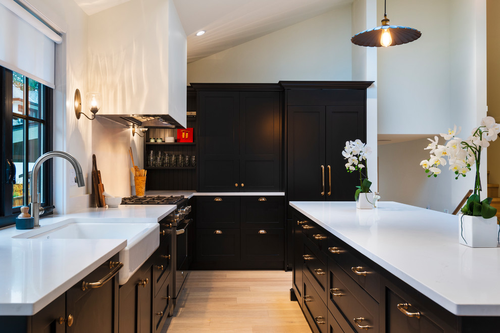 Mid-sized mountain style l-shaped light wood floor and beige floor open concept kitchen photo in Vancouver with a farmhouse sink, shaker cabinets, black cabinets, quartz countertops, paneled appliances, an island and white countertops