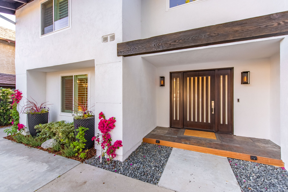 Expansive transitional front door in Los Angeles with white walls, slate floors, a double front door, a medium wood front door, multi-coloured floor and vaulted.