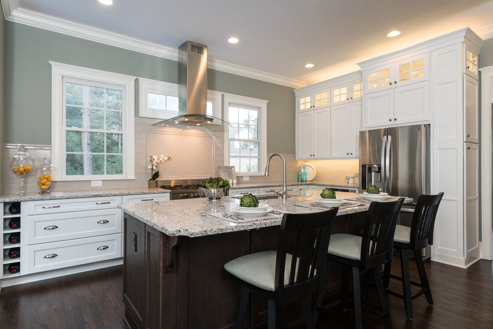 Inspiration for an expansive transitional l-shaped eat-in kitchen in Atlanta with an undermount sink, recessed-panel cabinets, white cabinets, granite benchtops, grey splashback, porcelain splashback, stainless steel appliances, dark hardwood floors, with island, brown floor and white benchtop.