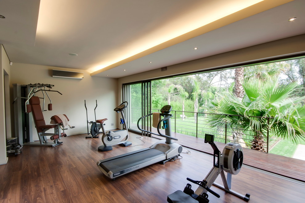 Inspiration for a large contemporary multipurpose gym in Other with beige walls and brown floor.